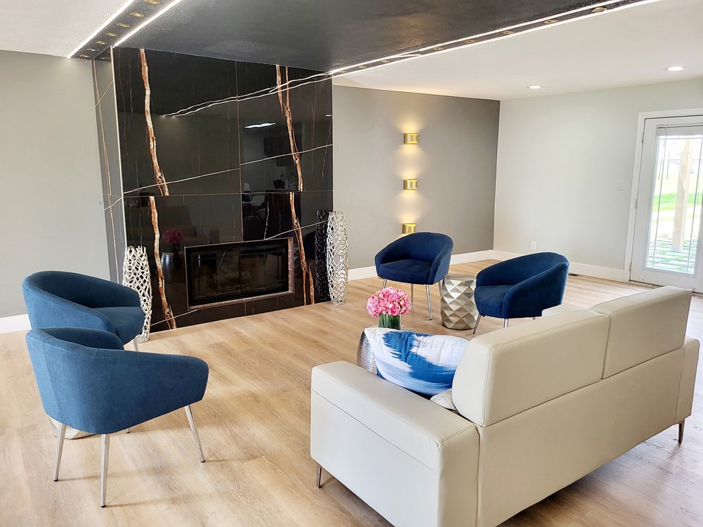 A living room with a fireplace and blue chairs.