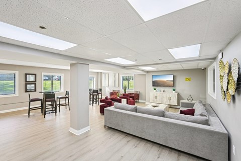 A spacious living room with a grey sofa and a dining table with chairs.