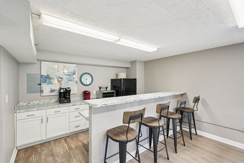 A kitchen with a white counter and chairs.