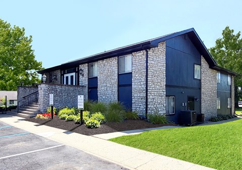 the front of a blue building with a sidewalk and grass