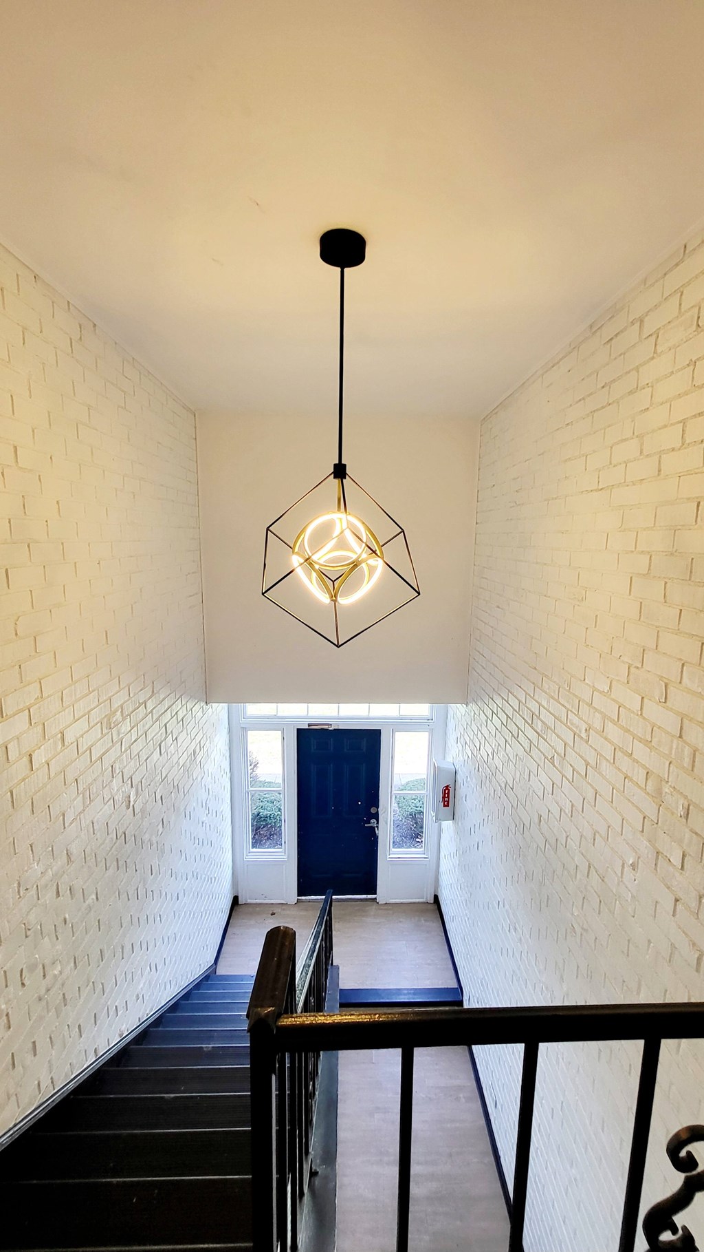 A white brick wall with a light hanging from the ceiling.