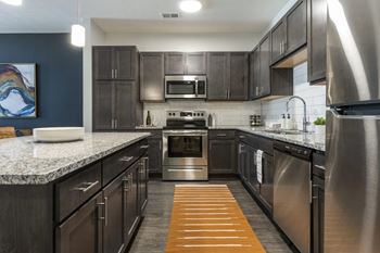 A modern kitchen with dark wood cabinets and stainless steel appliances.
