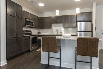 A kitchen with dark brown cabinets and a white countertop.