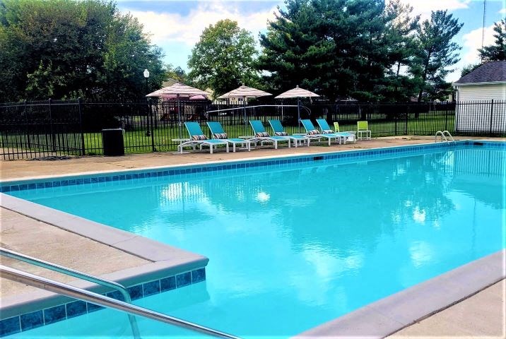 Fenced-in outdoor pool with several lounge chairs. 