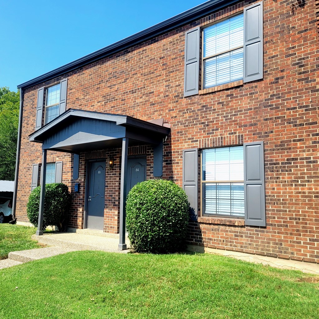 A red brick house with a blue door and a small porch.