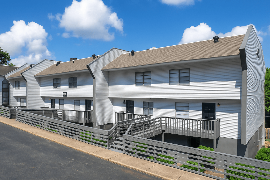 A white building with a grey roof and a metal fence in front.