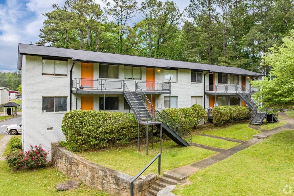 A white apartment building with orange doors and windows.