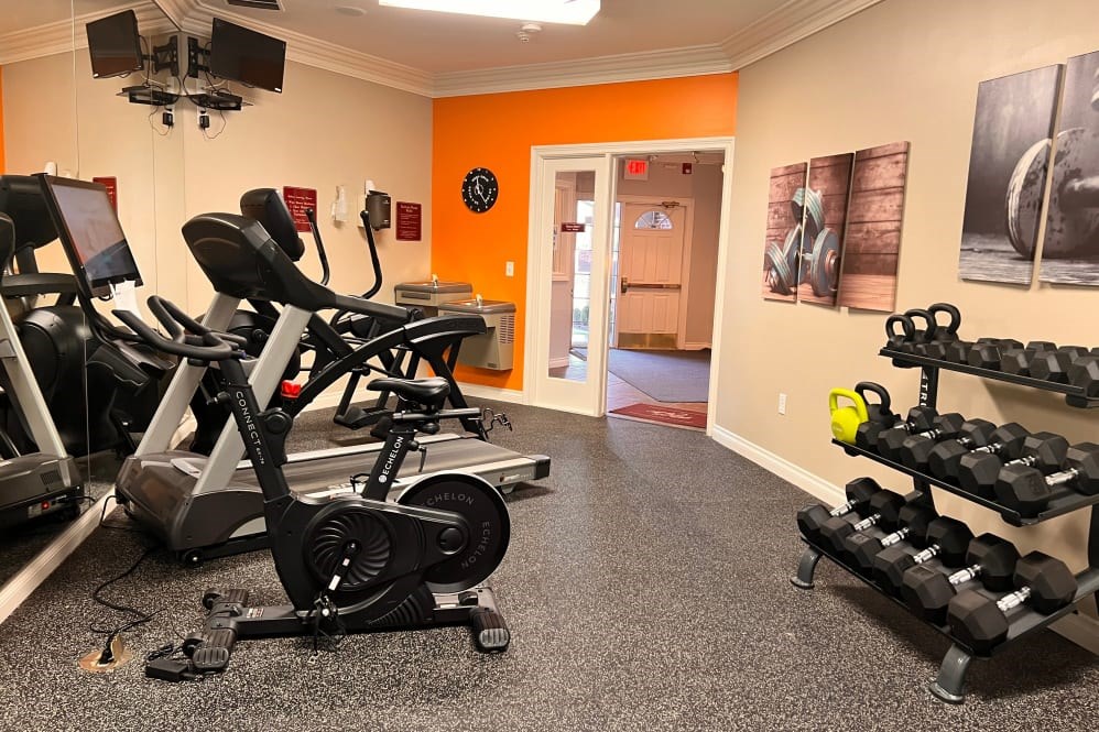 A gym with orange walls and a variety of exercise equipment.