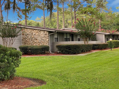 A house with a stone wall and a green lawn.