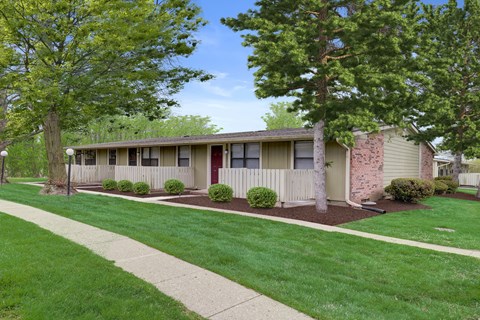 A row of houses with green lawns and trees in the background.