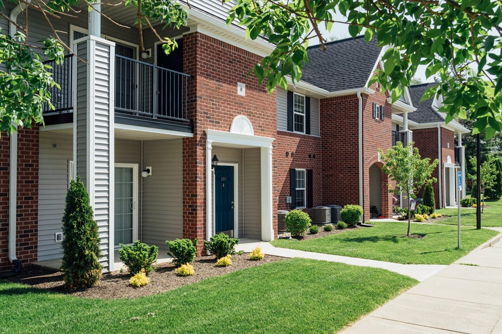 a brick building with a porch and a sidewalk