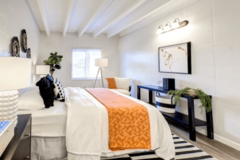 A bedroom with a white bed and a black and white striped rug.