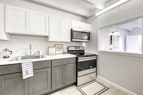 A kitchen with white cabinets and a black and white stove top oven.