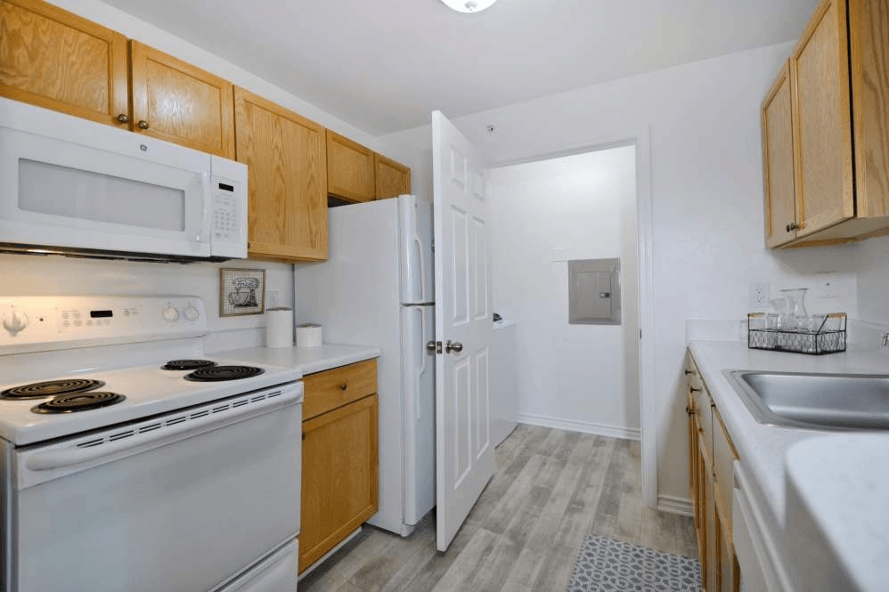 A kitchen with white appliances and wooden cabinets.