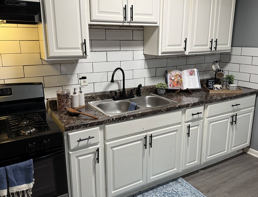 A kitchen with white cabinets and a black stove top.