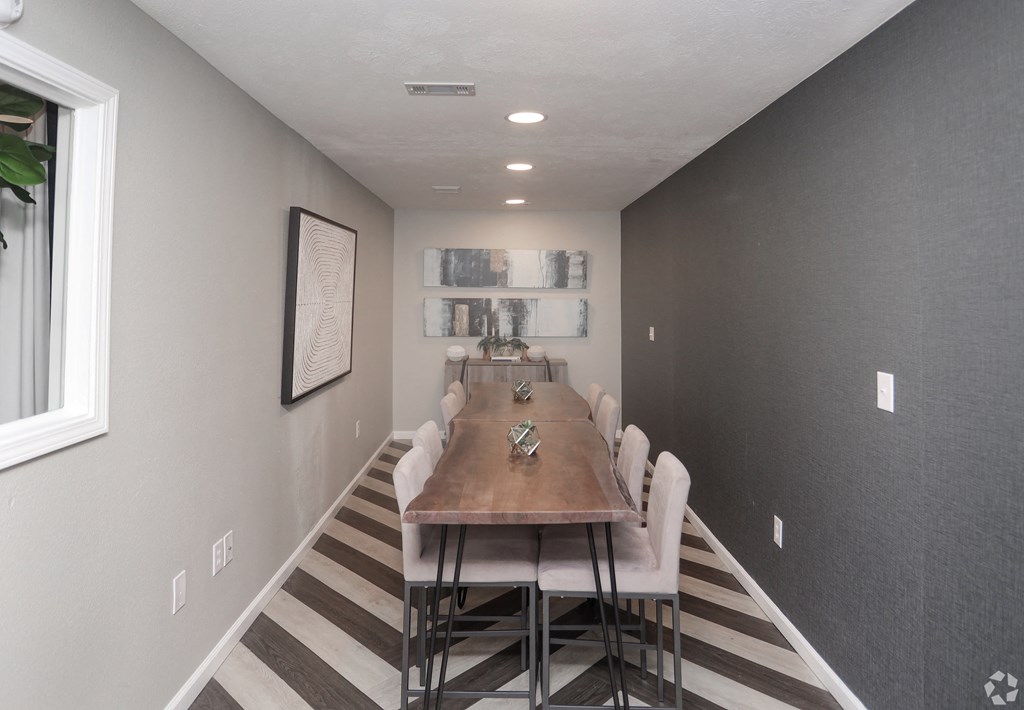 a dining room with a long wooden table and white chairs