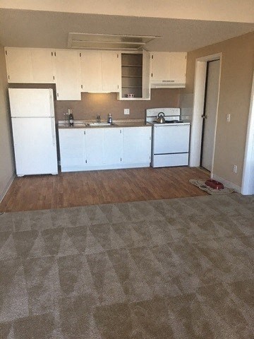 an empty kitchen with white appliances and white cabinets
