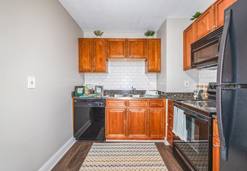 A kitchen with wooden cabinets and black appliances.