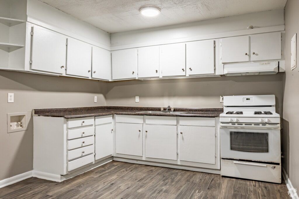 A kitchen with white cabinets and a white stove top oven.
