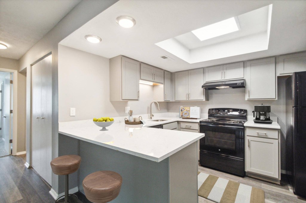 a white kitchen with black appliances and a white counter top