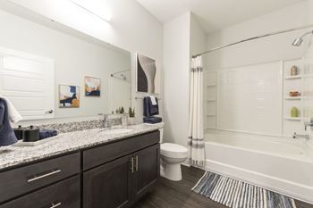 A bathroom with a white tub, sink, and toilet.