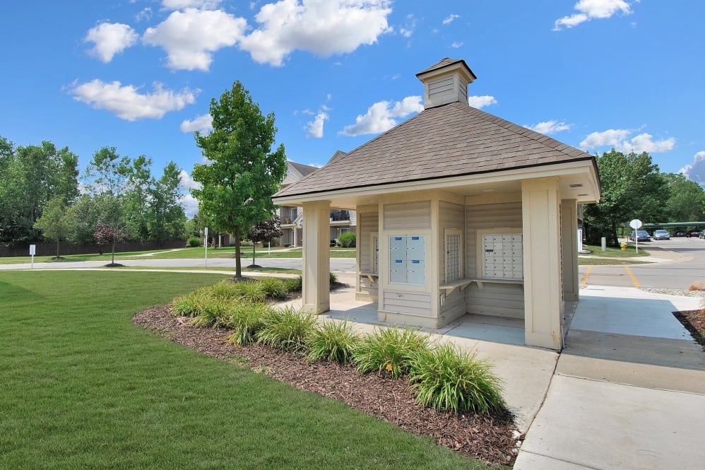 A small building with a brown roof and a signboard is surrounded by a well-maintained lawn.