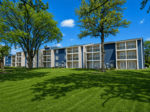 A large grassy area in front of a building with trees on either side.