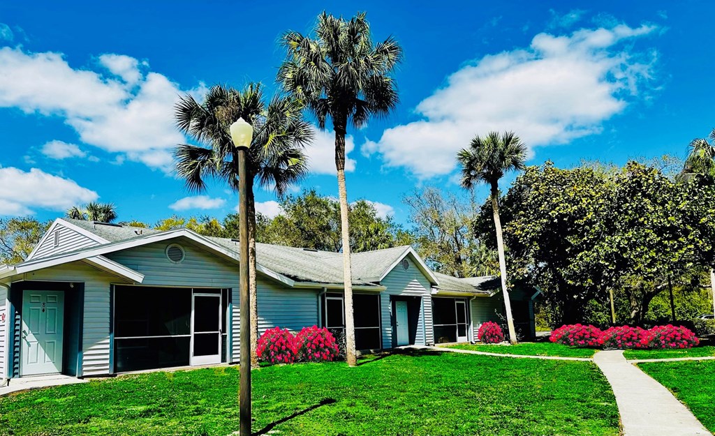 A blue house with palm trees in front of it at Aqua Bay Apartments in Naples, FL 34116