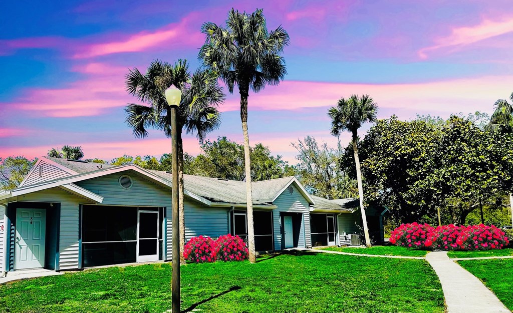 A blue house with palm trees in front of it at Aqua Bay Apartments in Naples, FL 34116