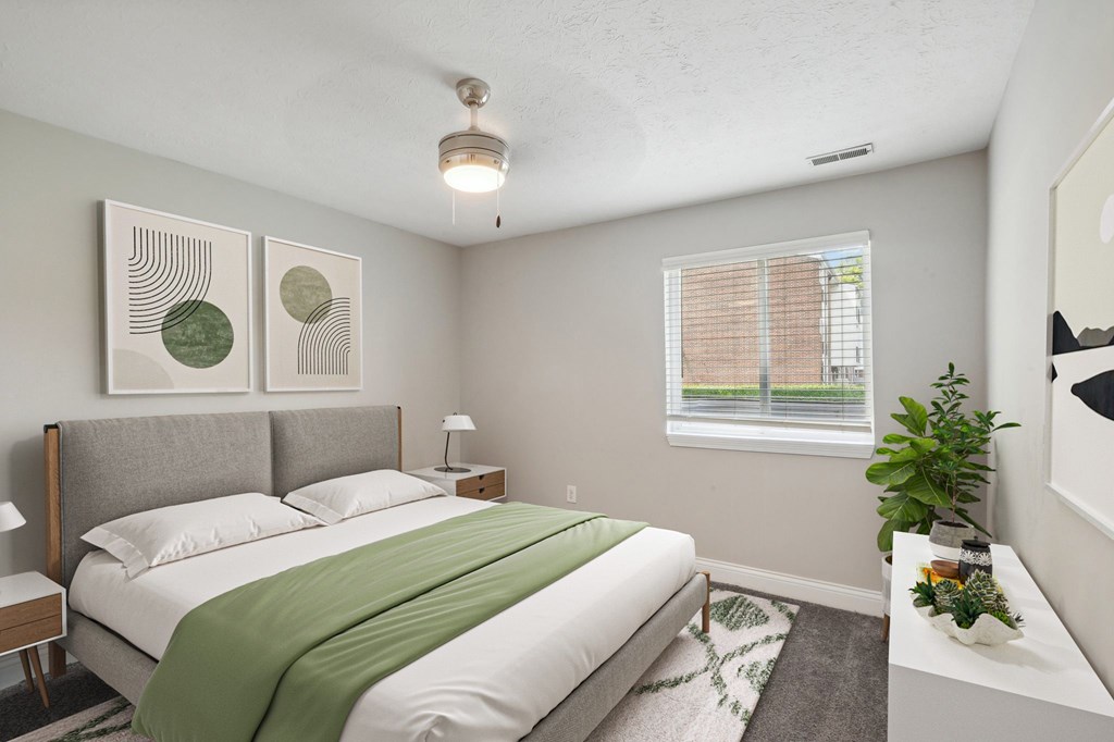 A bedroom with a bed, nightstand, and window.
