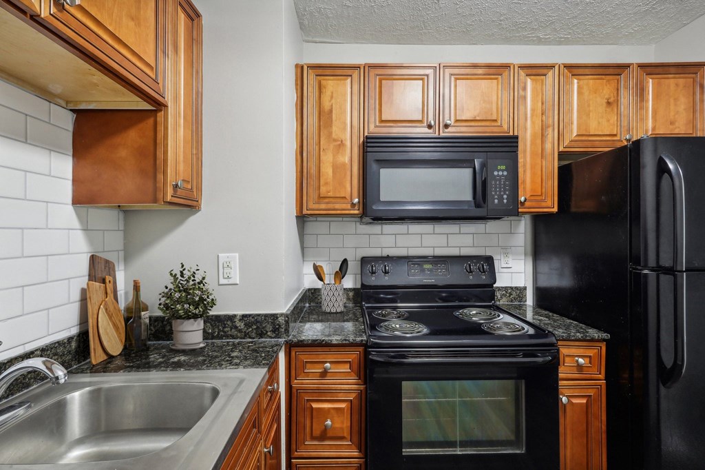 A kitchen with wooden cabinets and black appliances.
