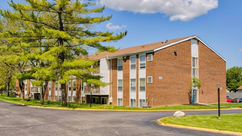 A brick apartment building with a parking lot in front.