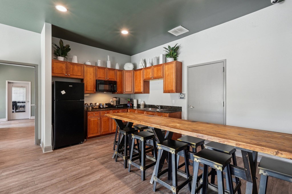 A kitchen with a black fridge and wooden bar stools.