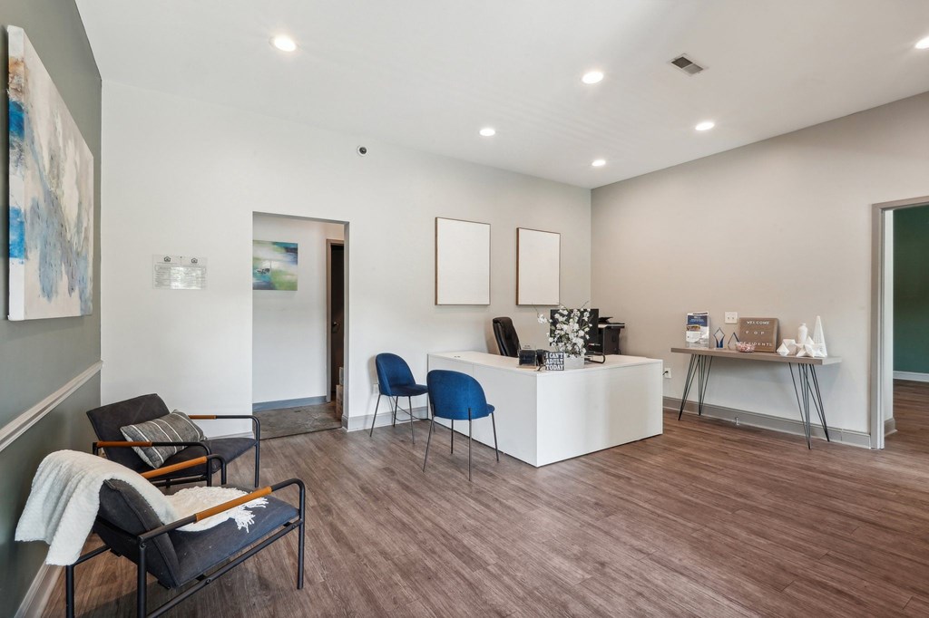 A room with a white reception desk and blue chairs.