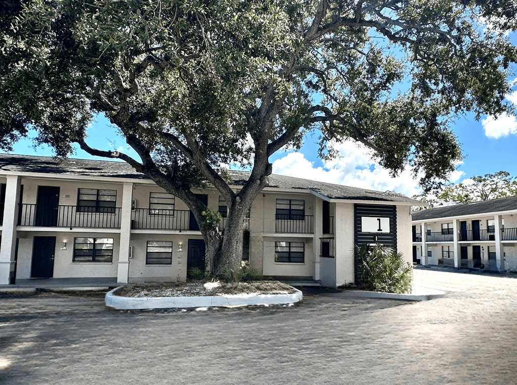 A tree in front of a building with a white and black facade.