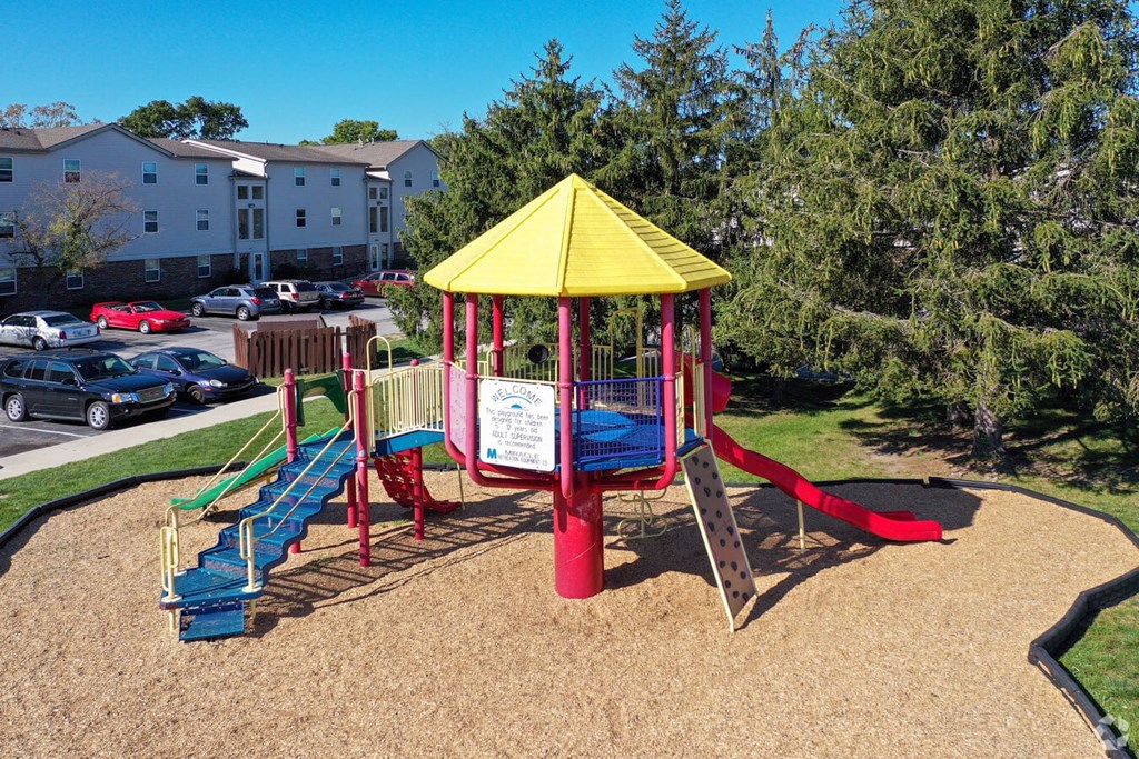 A playground with a yellow canopy and red and blue slides.