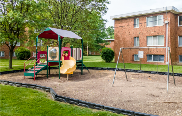 a playground with a swing set in front of a building