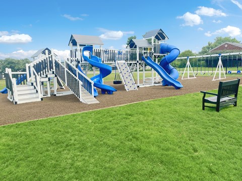 A playground with a blue slide and a green bench.