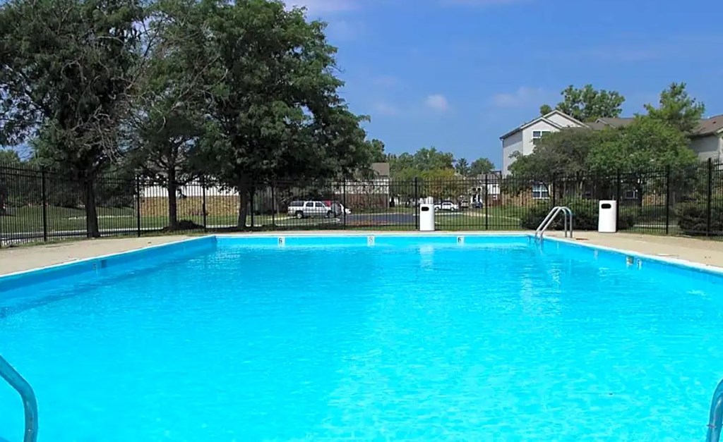 A large blue swimming pool surrounded by a black fence.