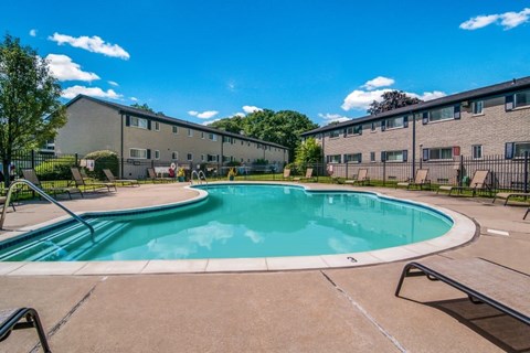 A swimming pool in a sunny day surrounded by a fence.