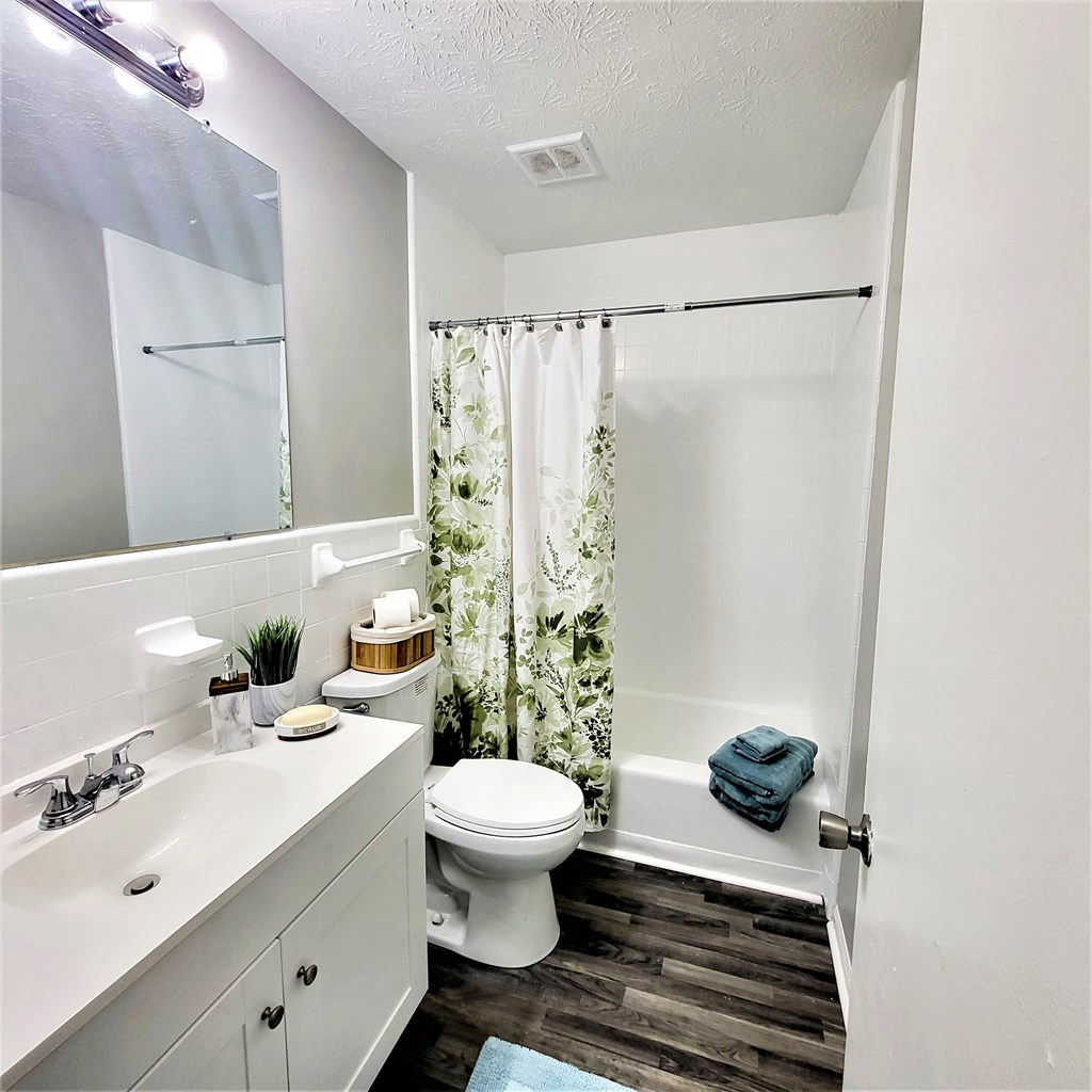 a bathroom with a white sink and toilet next to a bathtub with a shower curtain