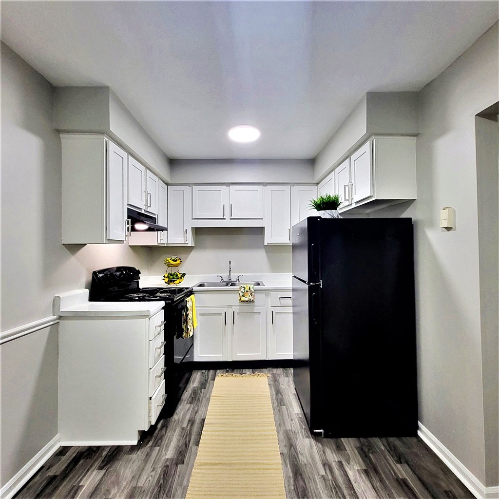a small kitchen with white cabinets and black appliances