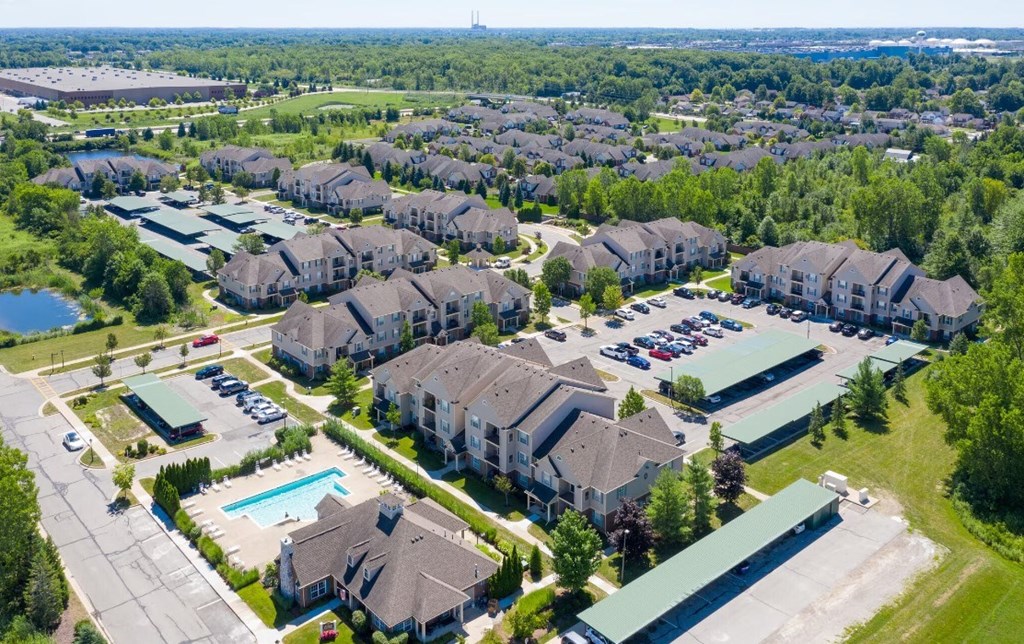 A bird's eye view of a residential area with houses, a swimming pool, and a parking lot.