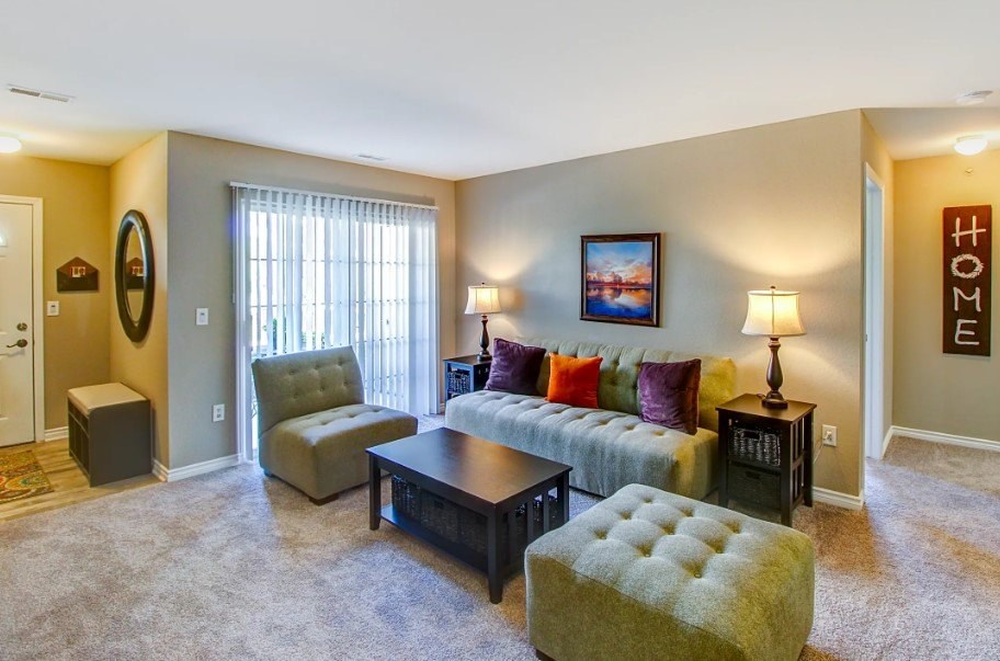 A living room with a couch, chair, ottoman, and lamp.