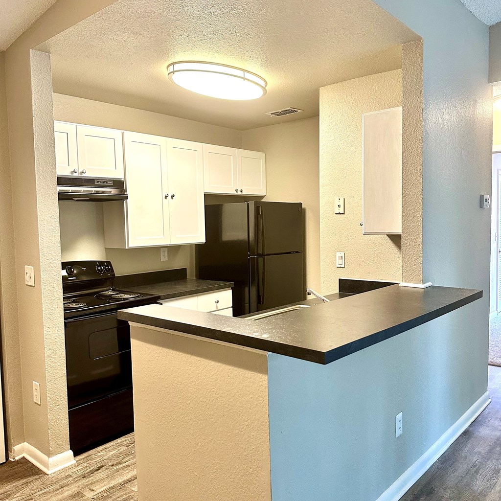 a kitchen with a countertop a kitchen with a countertop and a black refrigerator at Aqua Bay Apartments in Naples, FL 34116