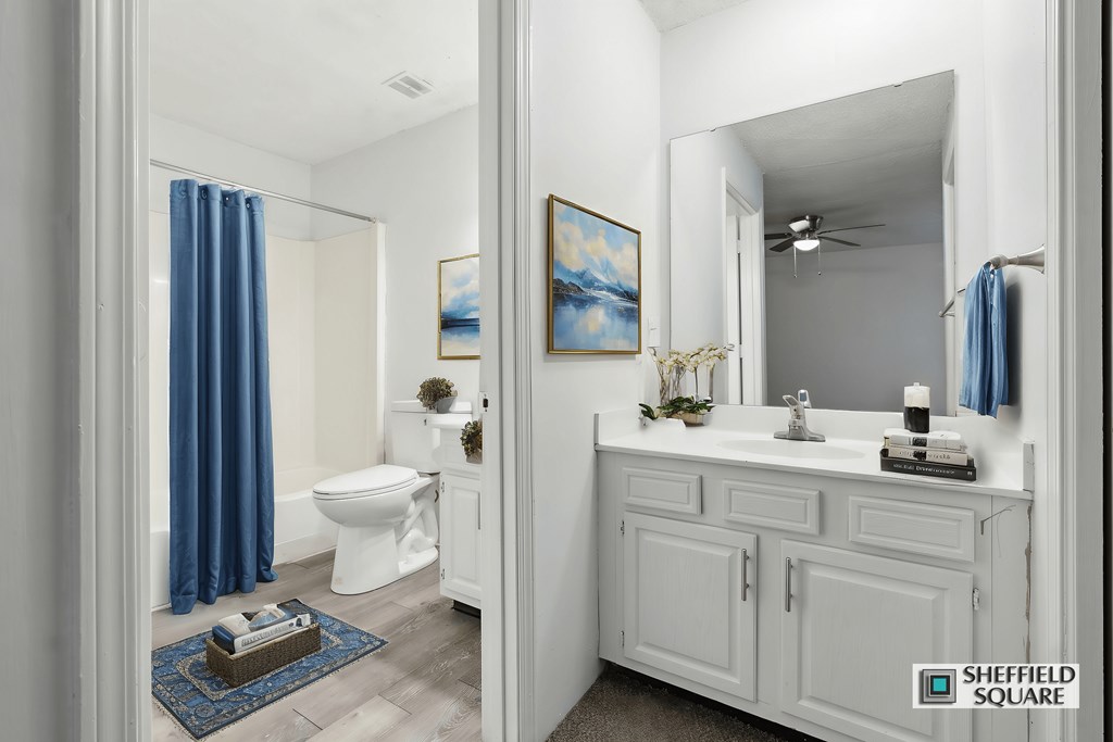 A bathroom with a white toilet and a white sink with a blue curtain.
