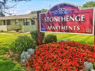 a sign for stonehenge apartments in front of a garden