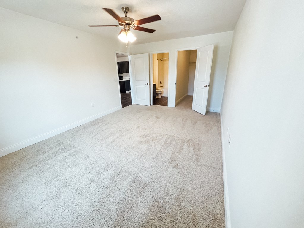 an empty living room with white walls and a ceiling fan