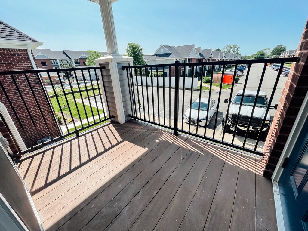 a balcony with a wooden floor and a black railing with a balcony fence