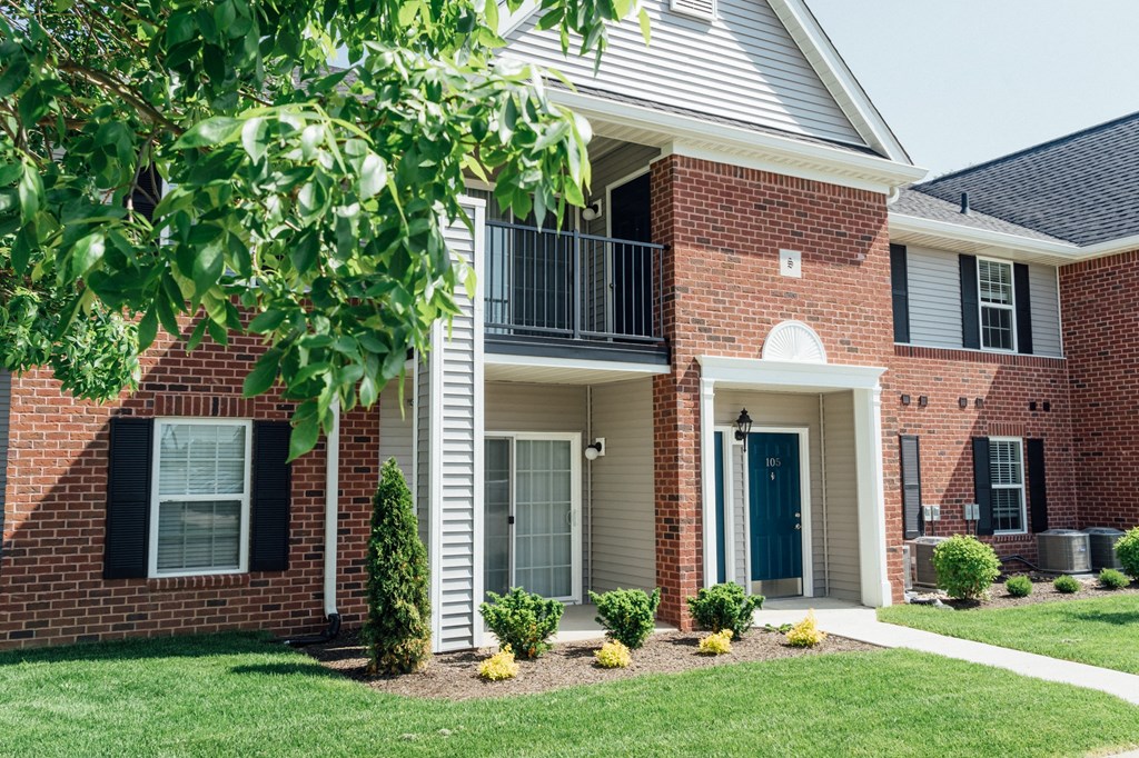 the outlook of a brick house with a balcony and a yard